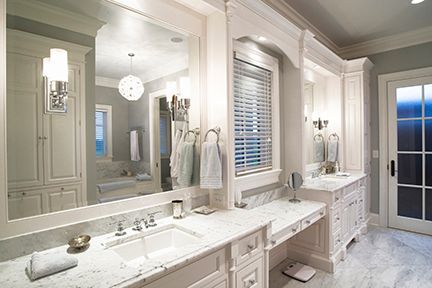 White bathroom with a large mirror over a double sink vanity, cabinets, and a window.