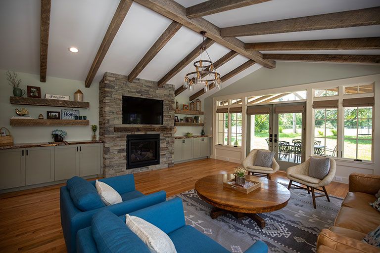 Living room with stone fireplace, blue couches, and wood beams.