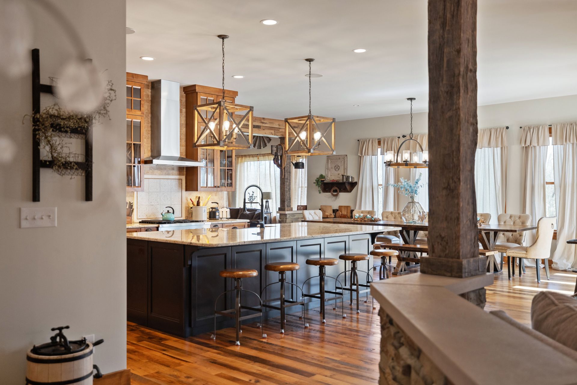 Open-concept kitchen with a large island, wood accents, and hanging lights. Dining area visible in the background.
