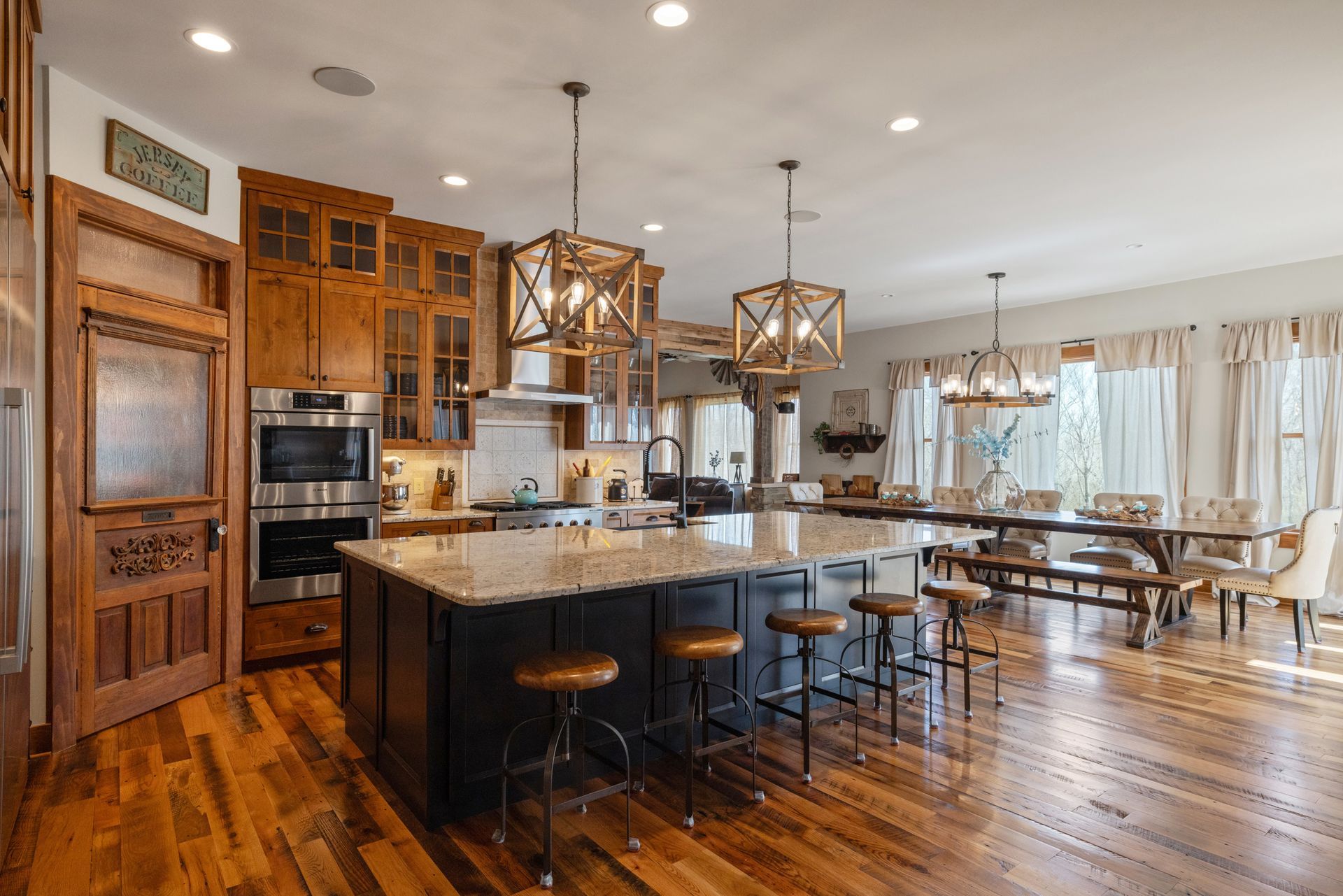Spacious kitchen with a large island, wooden cabinets, and a long dining table.