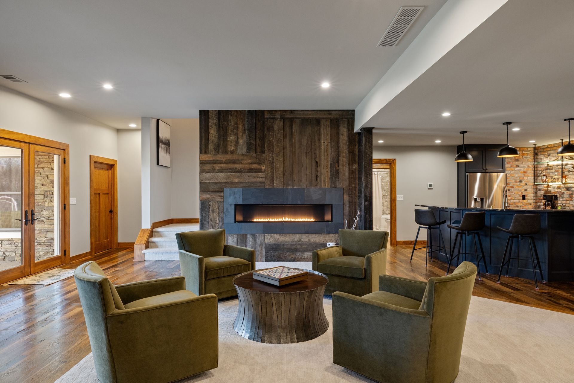 Cozy living room with fireplace, green armchairs, and a rustic wood accent wall.