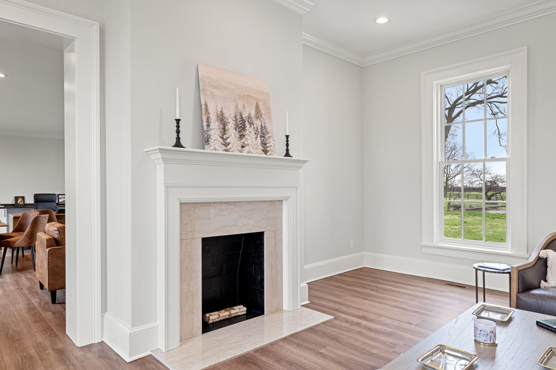 Living room with fireplace, window, and wooden floor. Light gray walls and trim.