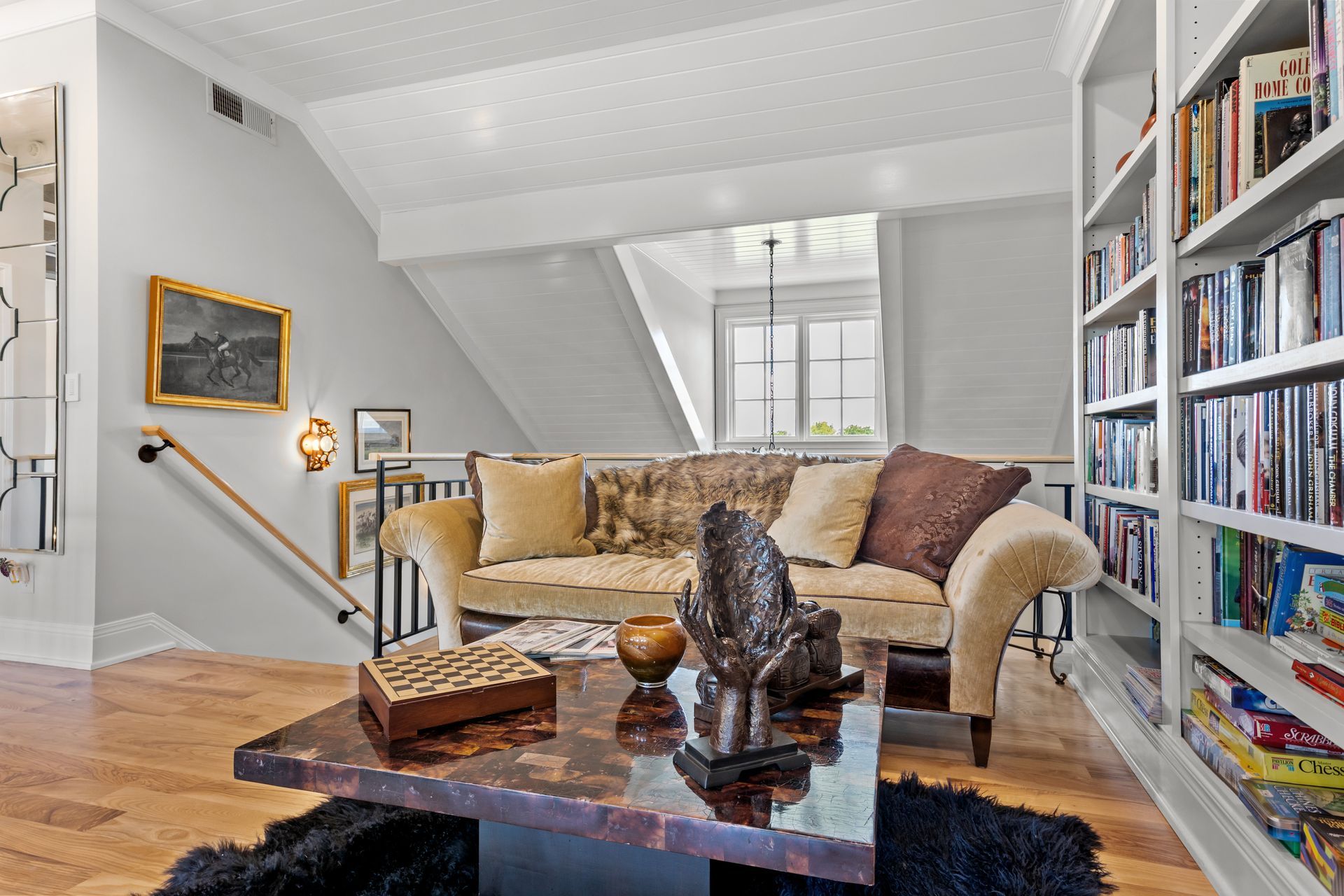 A cozy reading nook with a sofa, bookshelves, and a dark wood coffee table.