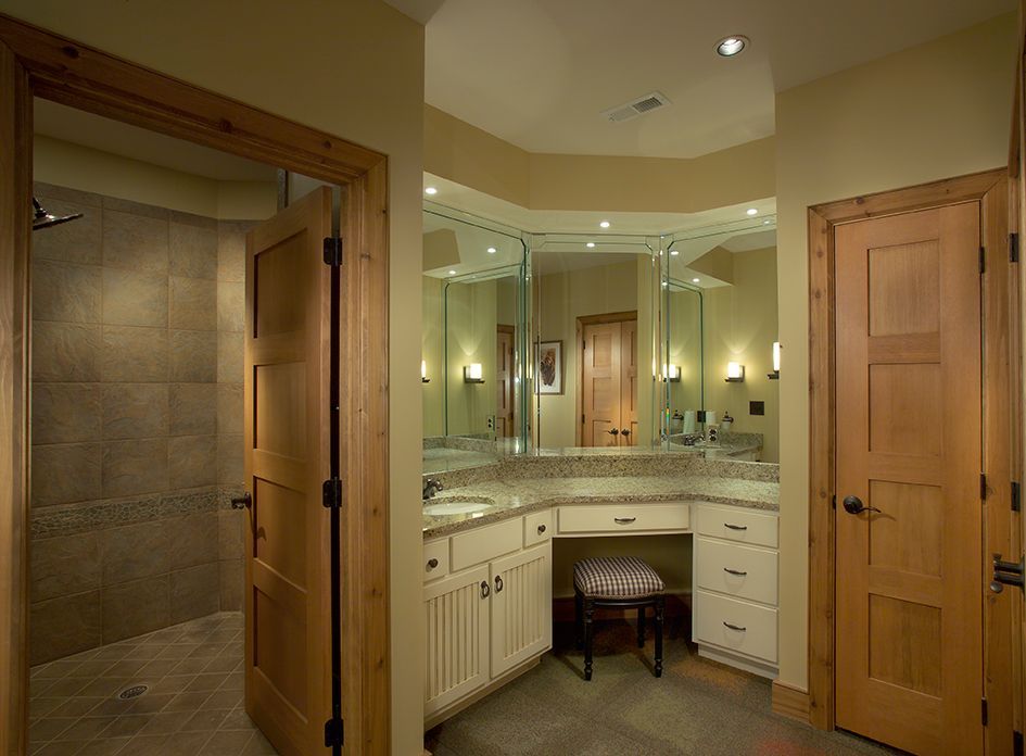 Bathroom with shower, vanity with two sinks, and a dressing table. Light wood doors and trim.