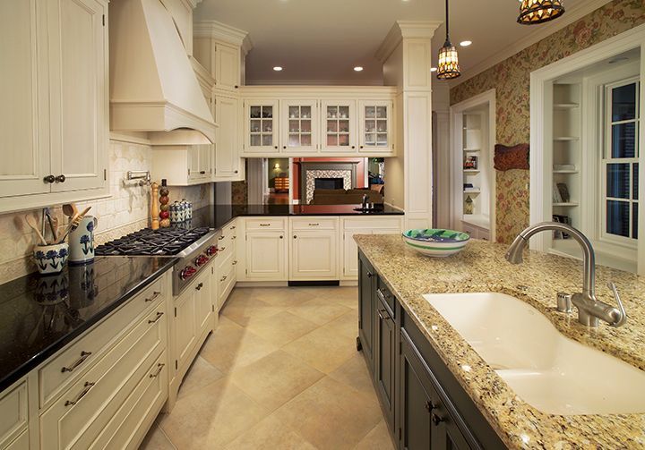 Kitchen with white cabinets, dark countertops, and a granite-topped island, illuminated by warm lighting.
