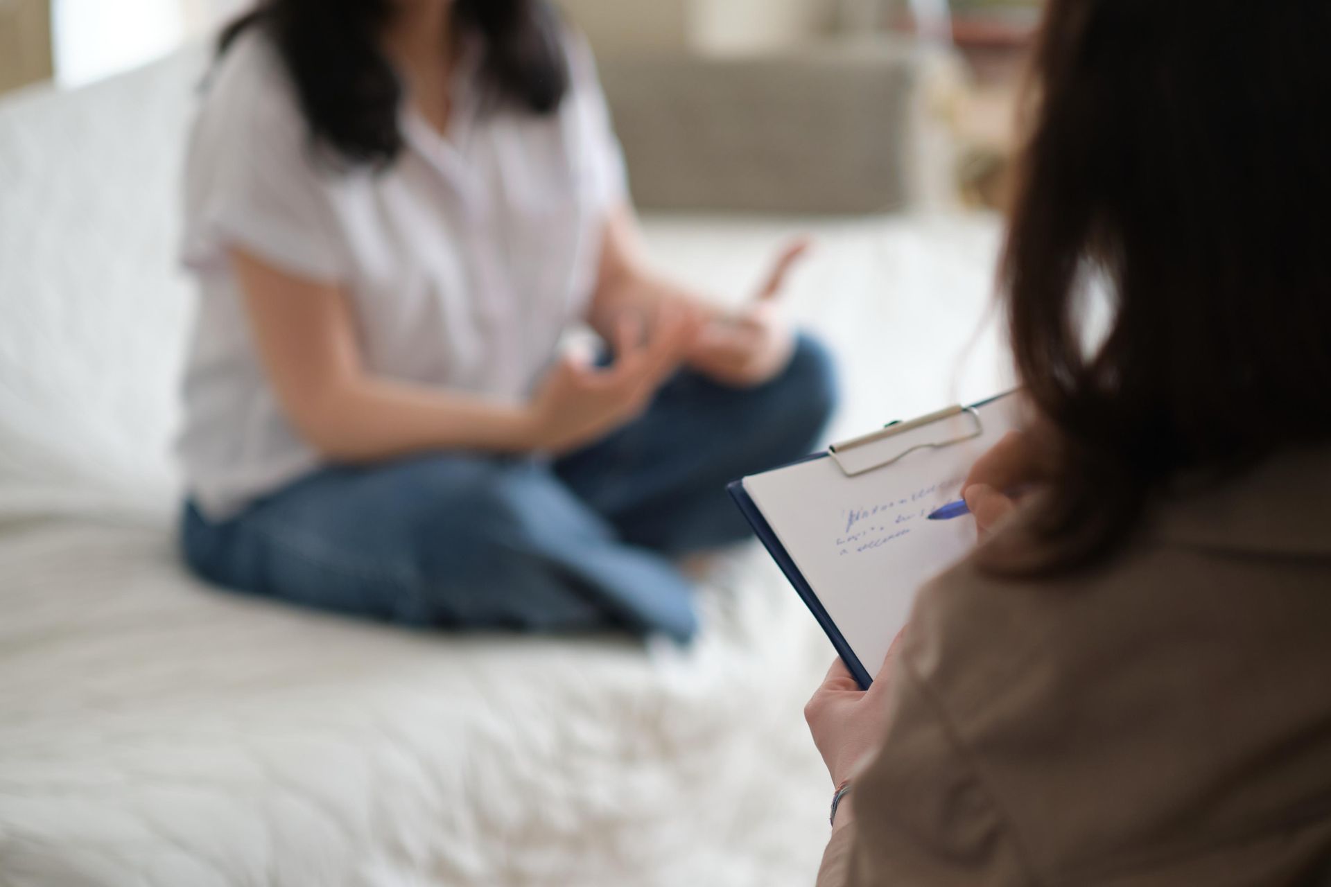 Person taking notes during a conversation on a bed in a bright room