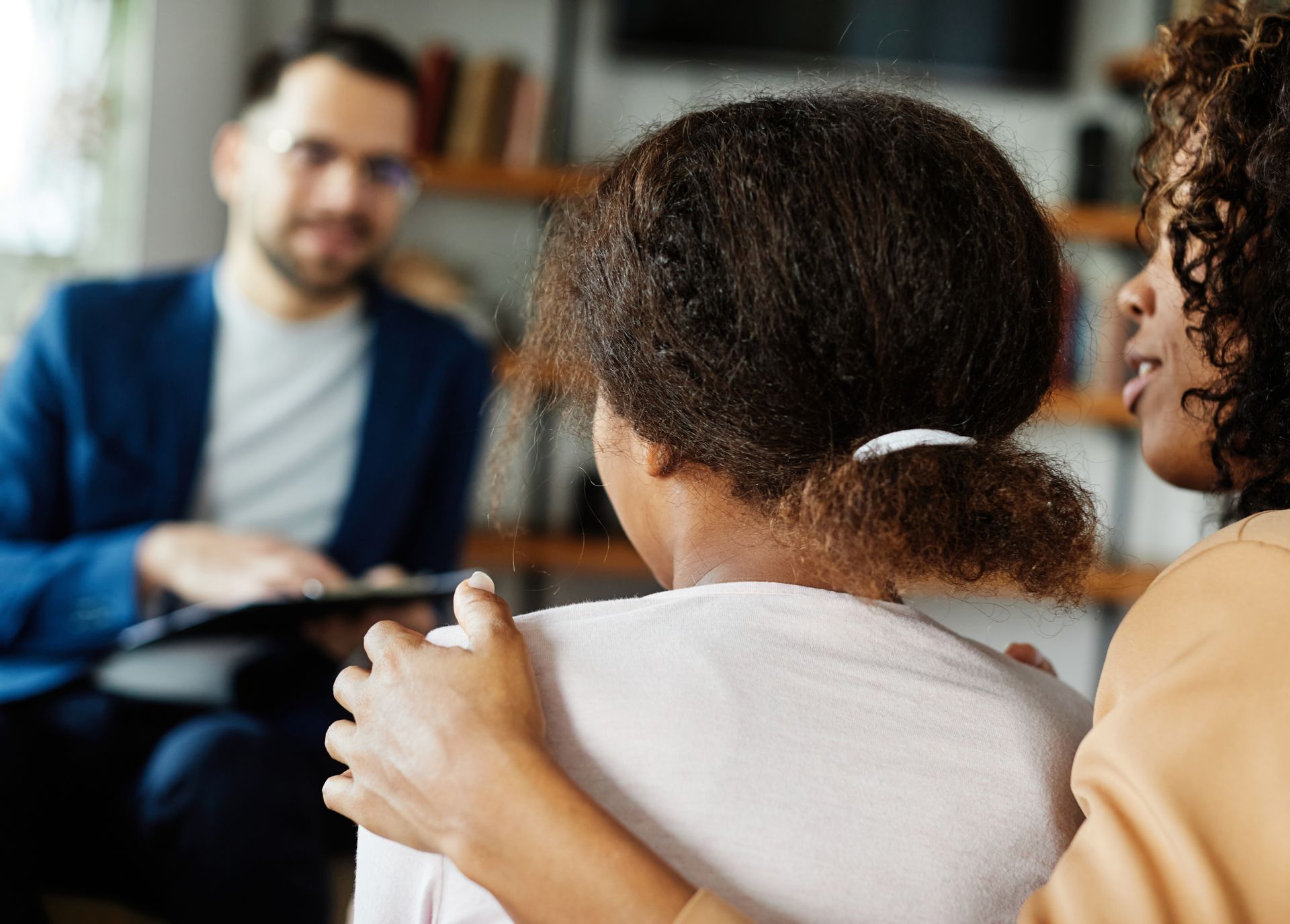 Counselor meeting with two seated people in a warm office setting