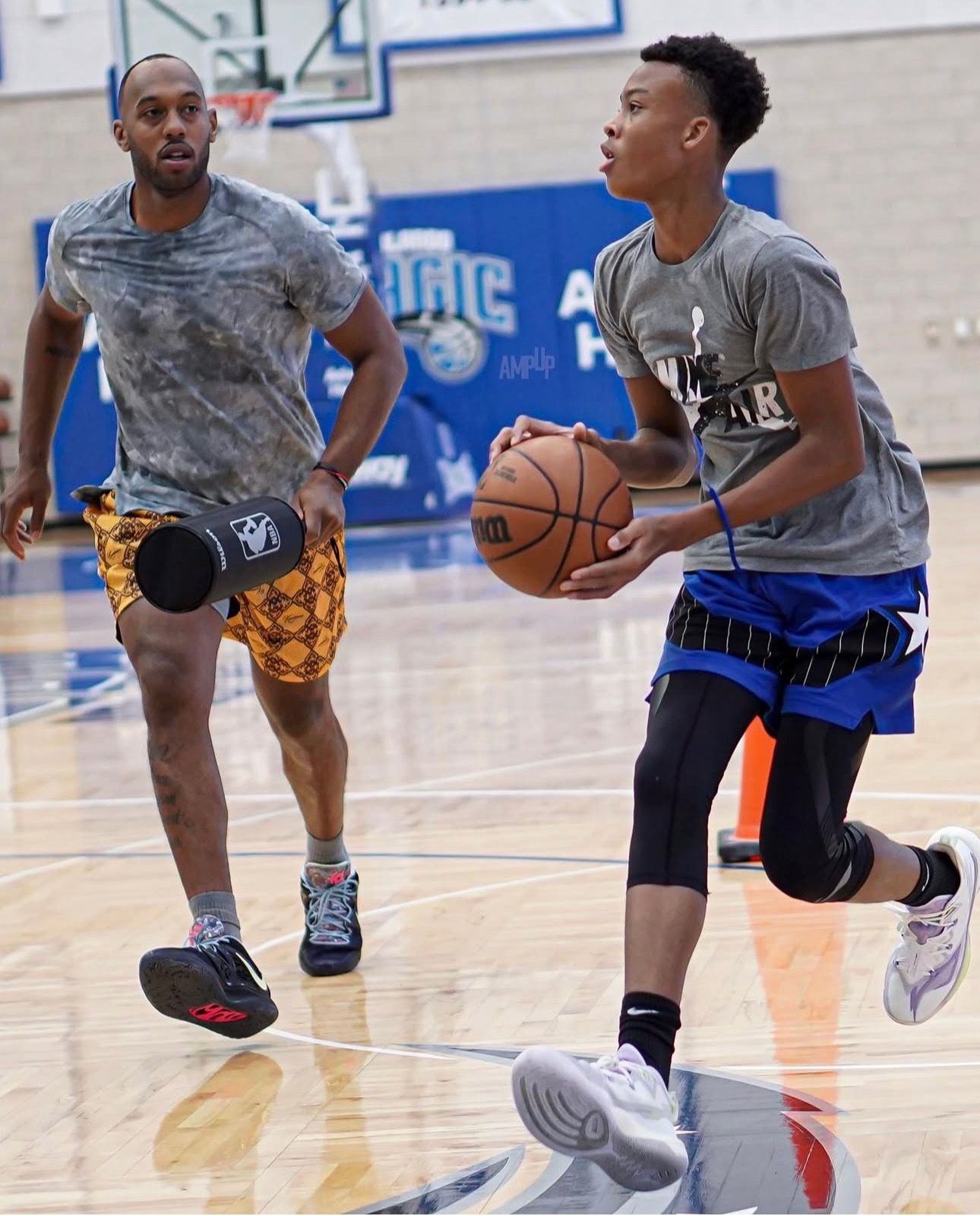Two men are playing basketball on a court with the word magic in the background