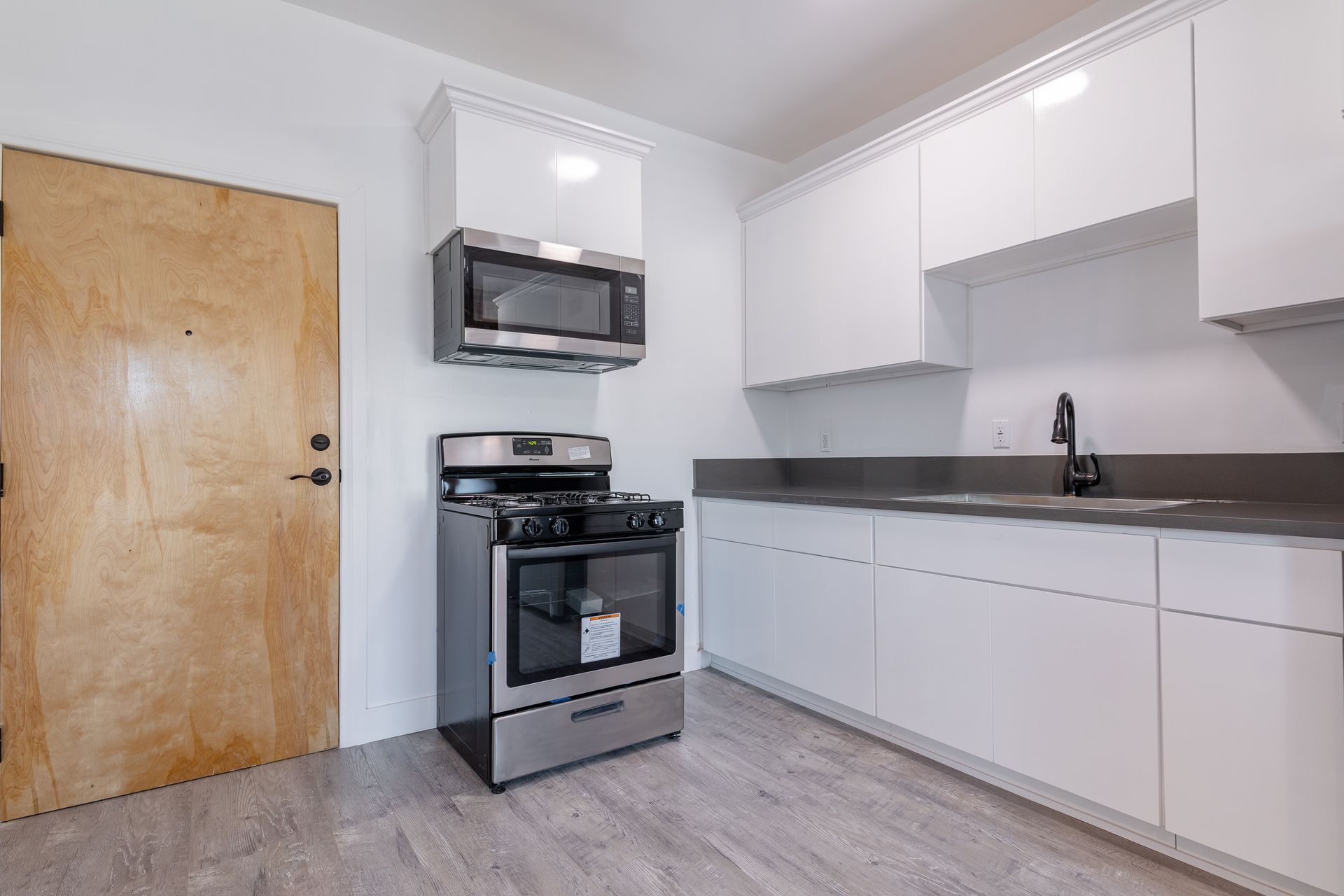 Interior with exposed brick wall, windows, and stainless steel refrigerator. A white pillar supports a small countertop.