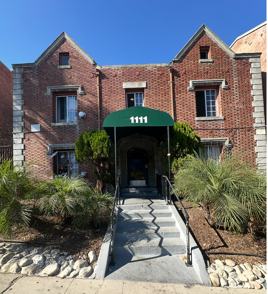 Two-story brick building with green awning over entrance marked
