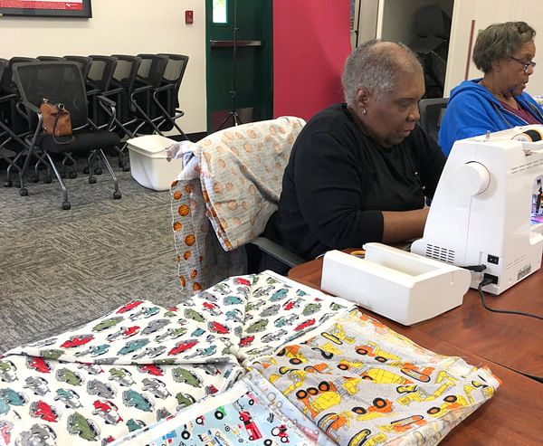A man is sitting at a table using a sewing machine.
