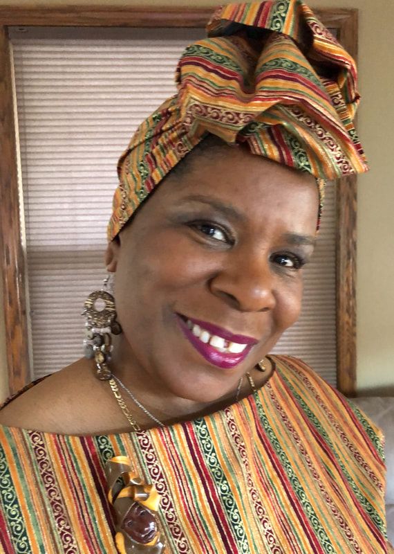 A woman wearing a head scarf and earrings is smiling for the camera.