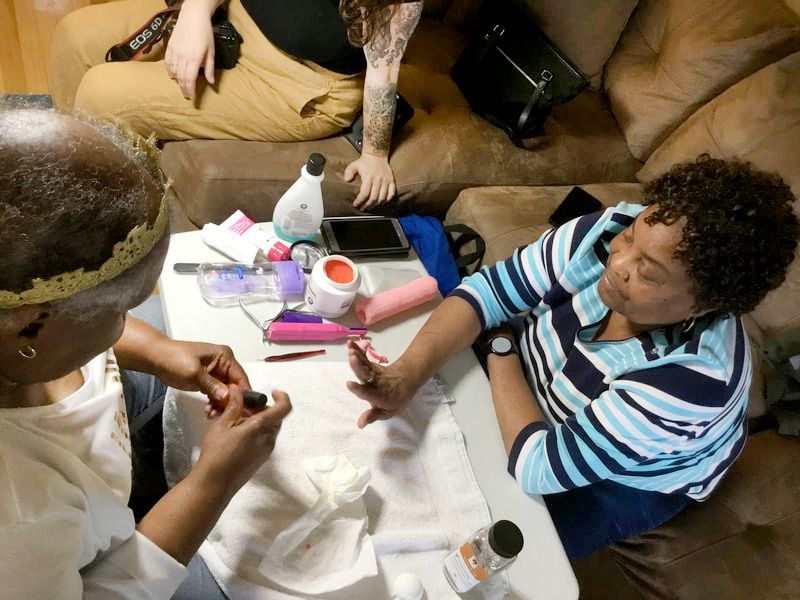 A woman is sitting at a table getting her nails painted