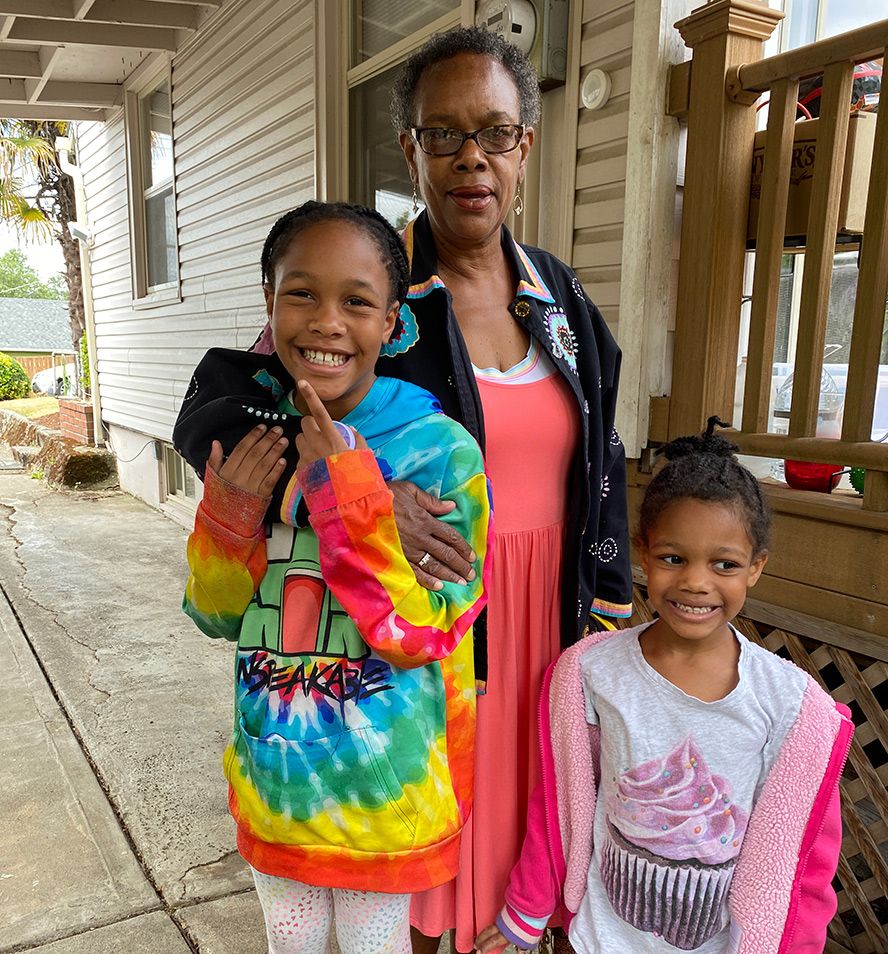 A woman and two children are posing for a picture in front of a house.