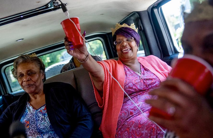 Two women are sitting in the back of a van holding red cups.