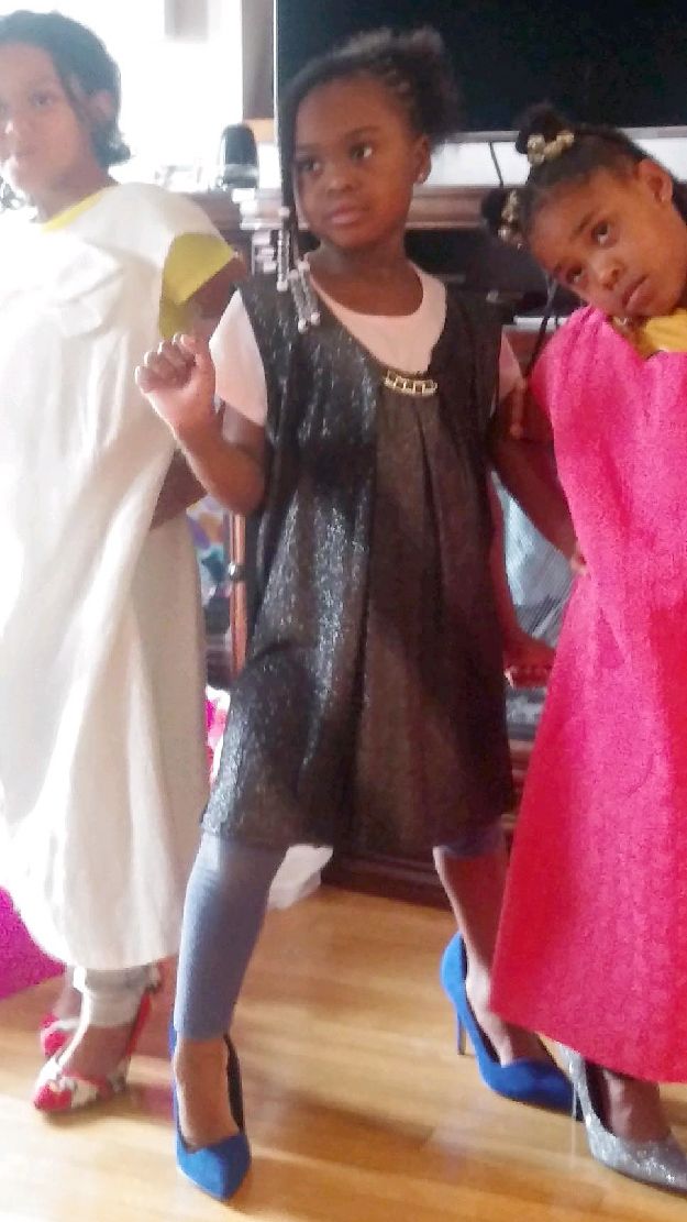 Three little girls are standing next to each other wearing different dresses