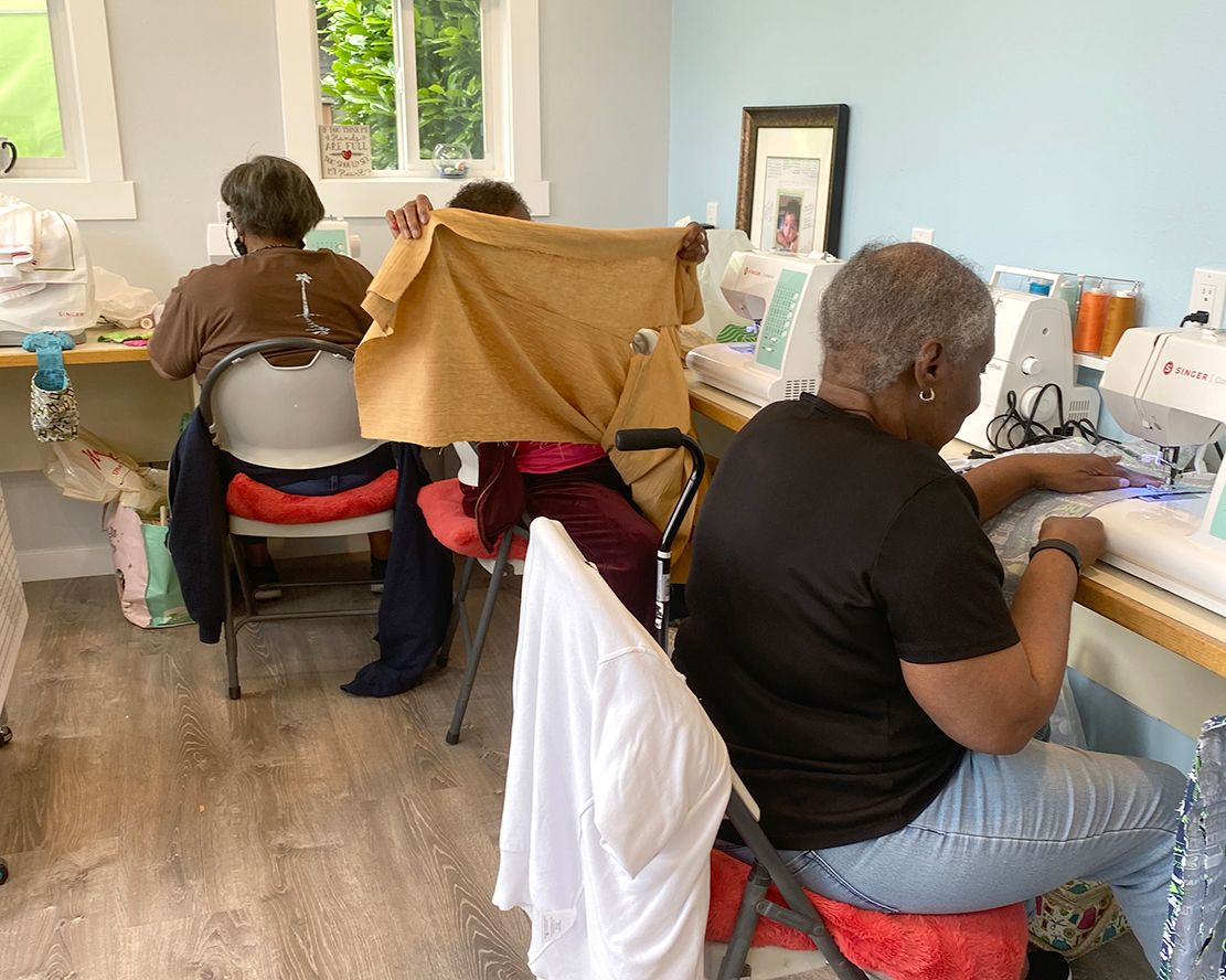 A group of women are sitting at sewing machines in a room.