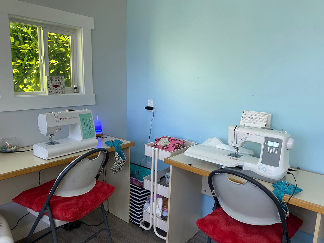Two sewing machines are sitting on a table in a room.