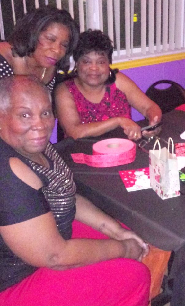 Three women are sitting at a table with a cake on it