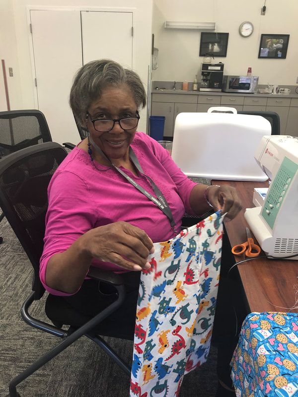 A woman in a pink shirt is sitting in front of a sewing machine