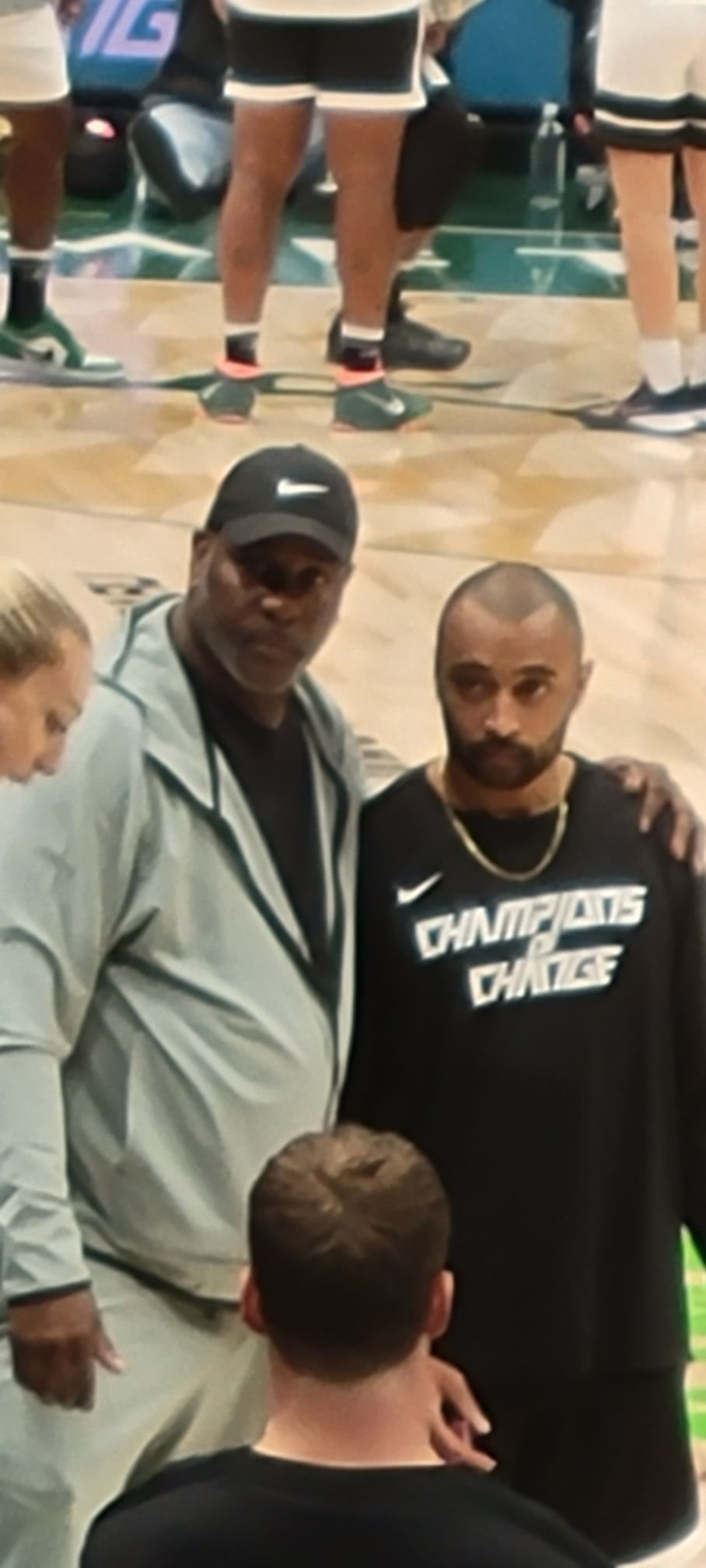 Two men are posing for a picture on a basketball court.