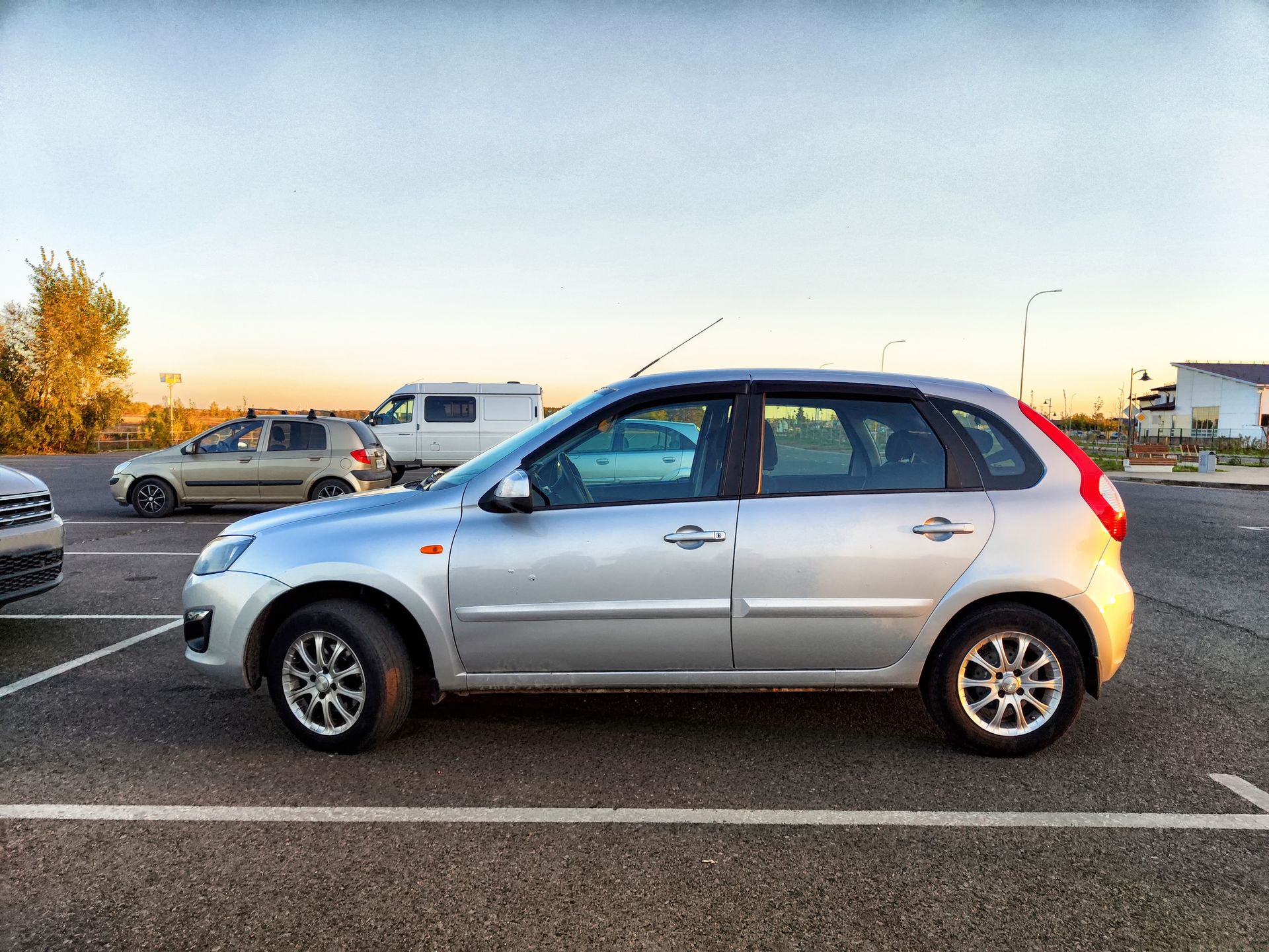 Silver hatchback car parked in a lot at sunset