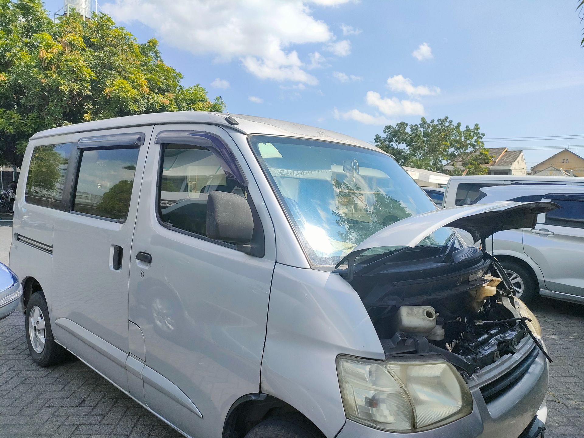 White van with its hood open, parked outdoors on a sunny day.