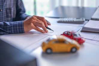 Hand drawing a car sketch beside toy cars on a desk with a laptop nearby Hand drawing a car sketch beside toy cars on a desk with a laptop nearby