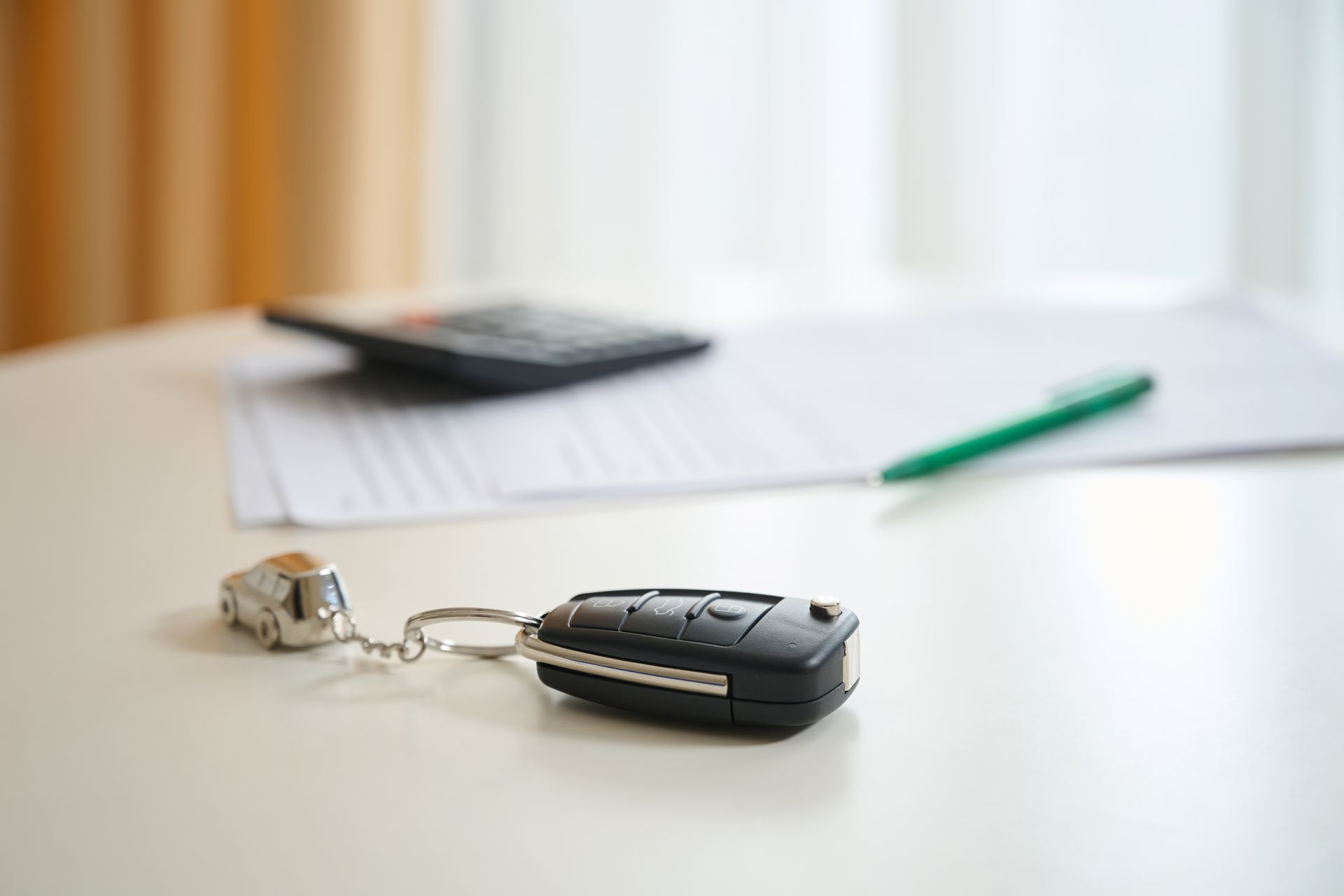 Car key fob on a white table with a smartphone and green pen in the background