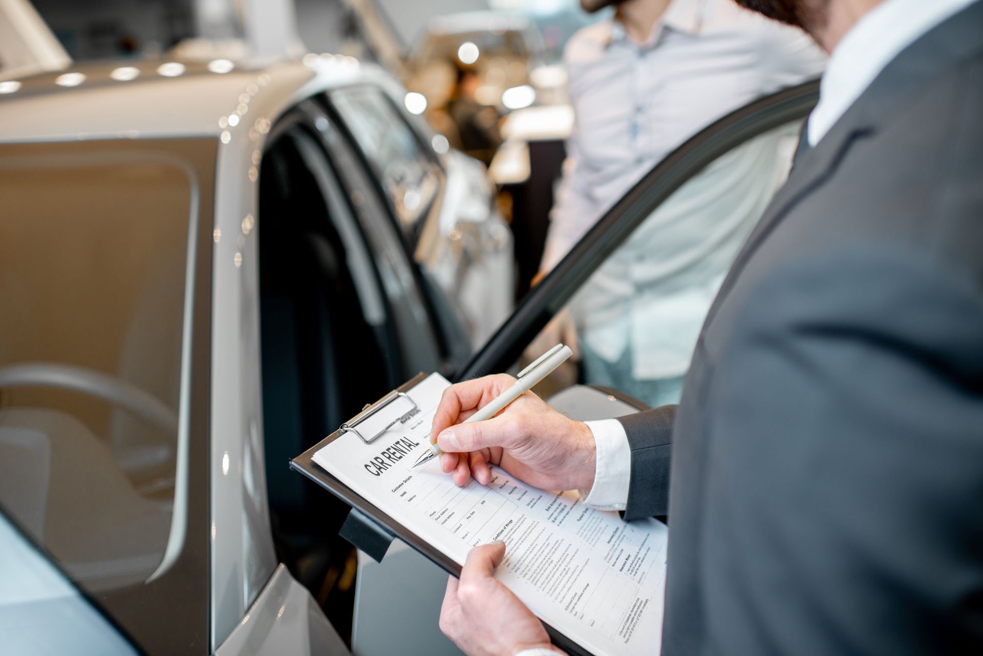 Person holding a clipboard beside an open car door, writing notes during a vehicle inspection Person holding a clipboard beside an open car door, writing notes during a vehicle inspection