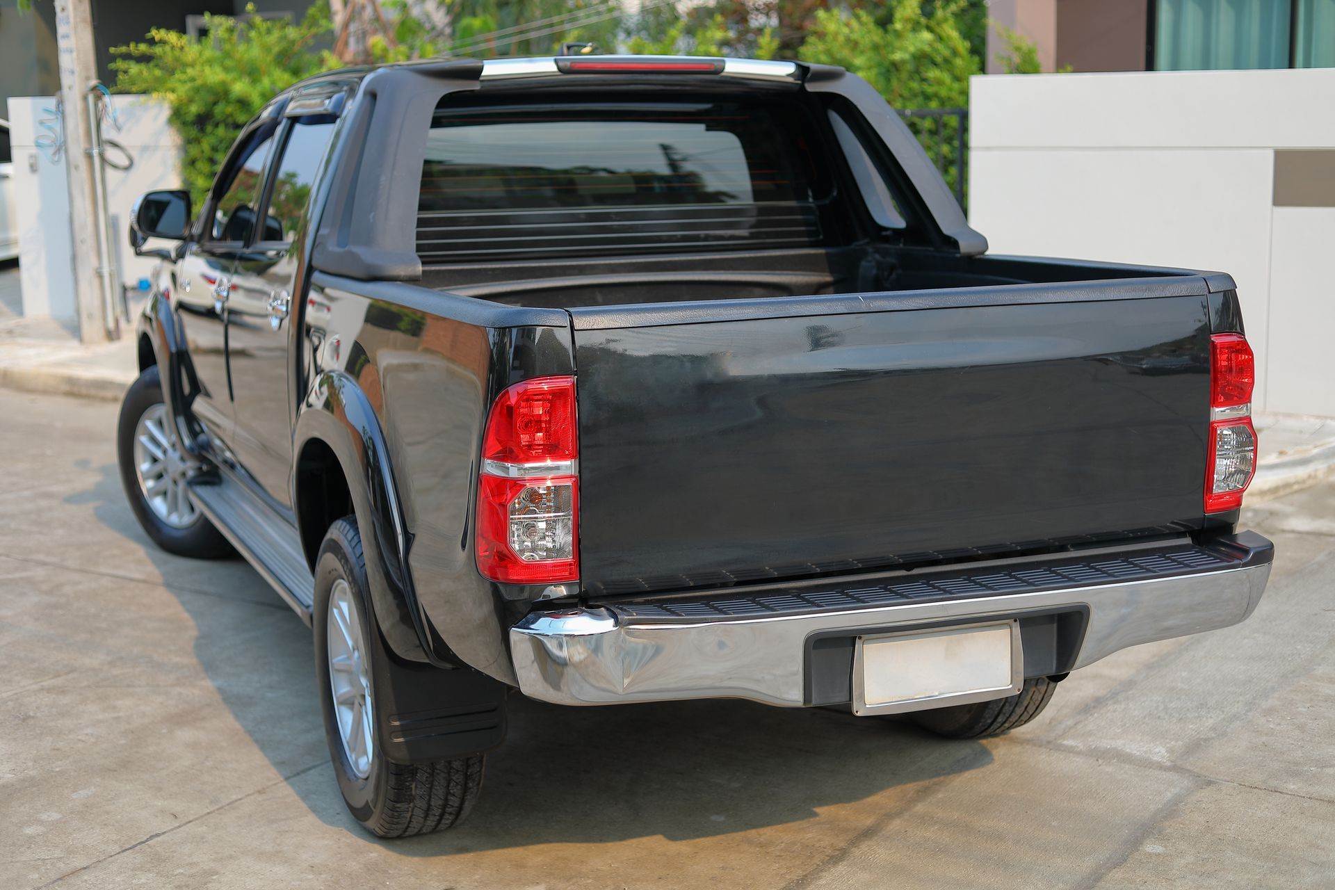 Black pickup truck parked in a driveway, rear view with chrome bumper and tinted windows Black pickup truck parked in a driveway, rear view with chrome bumper and tinted windows