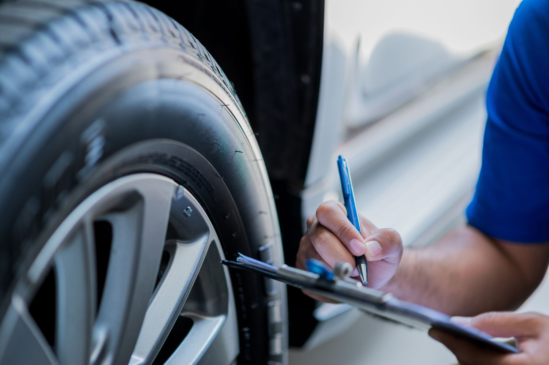 Mechanic checking a car tire with a clipboard and pen