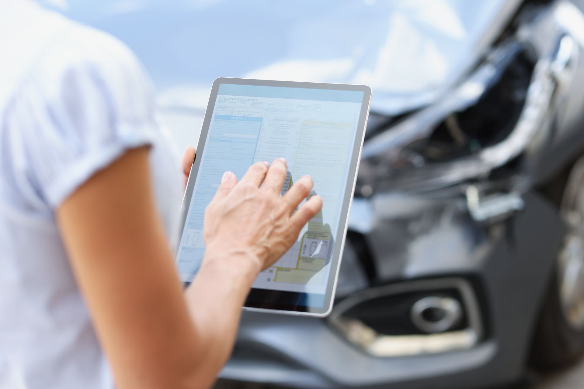 Person using a tablet near a motorcycle, with a hand tapping the screen. Person using a tablet near a motorcycle, with a hand tapping the screen.