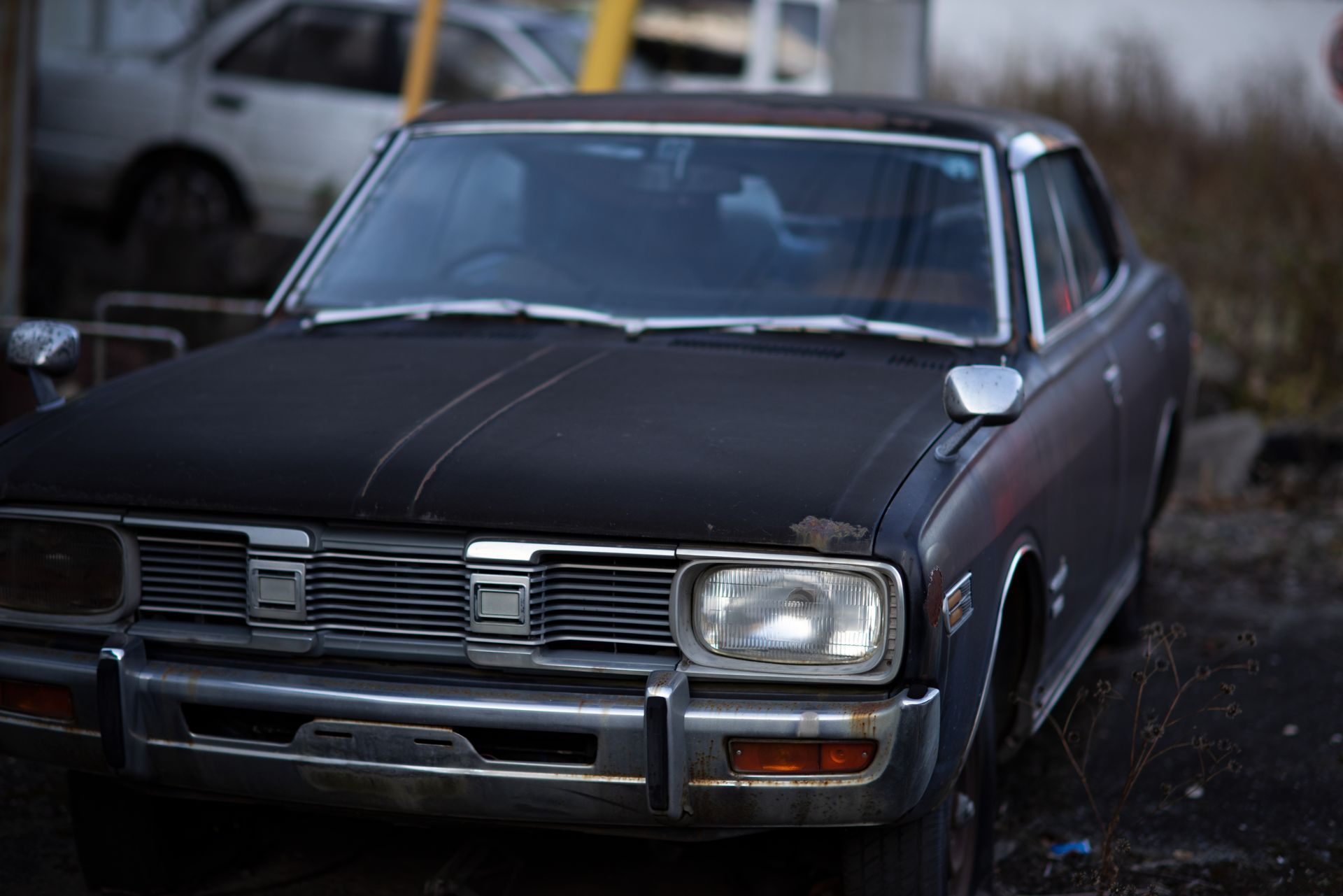 Dark vintage sedan parked outdoors in a wet driveway, front view. Dark vintage sedan parked outdoors in a wet driveway, front view.