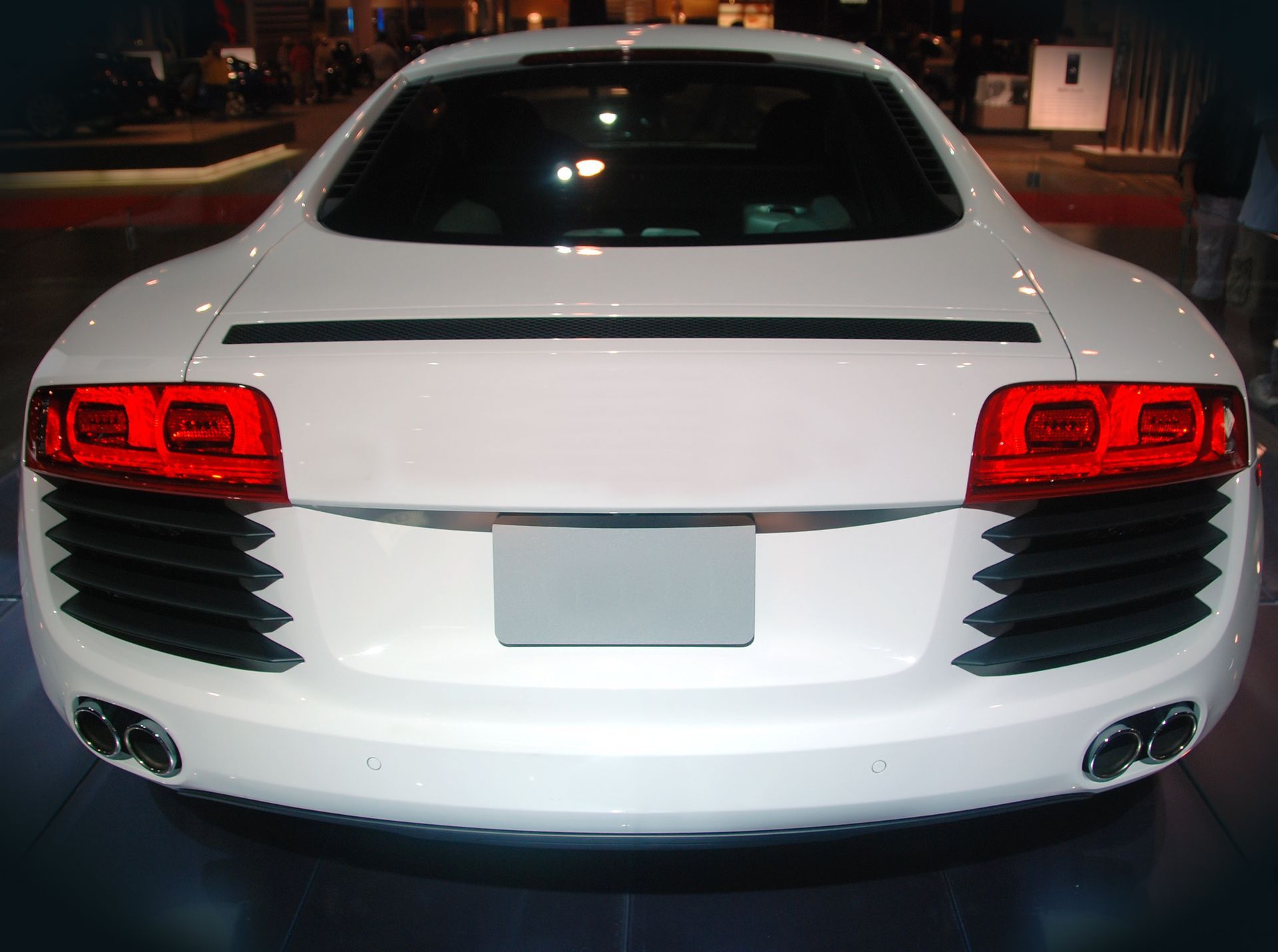 Rear view of a white sports car with red taillights parked at night.
