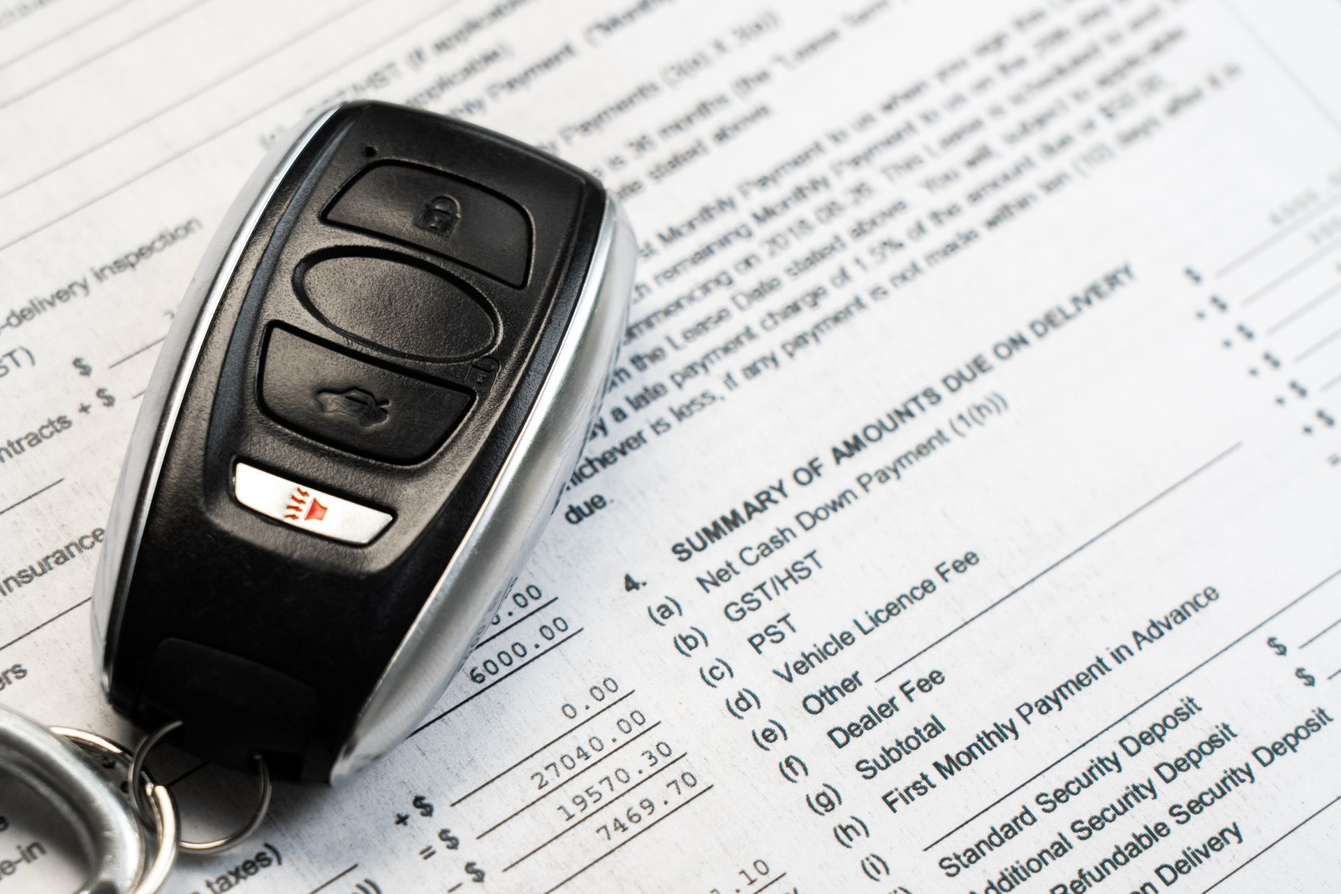 Car key fob on car insurance paperwork with visible policy details and checklist lines