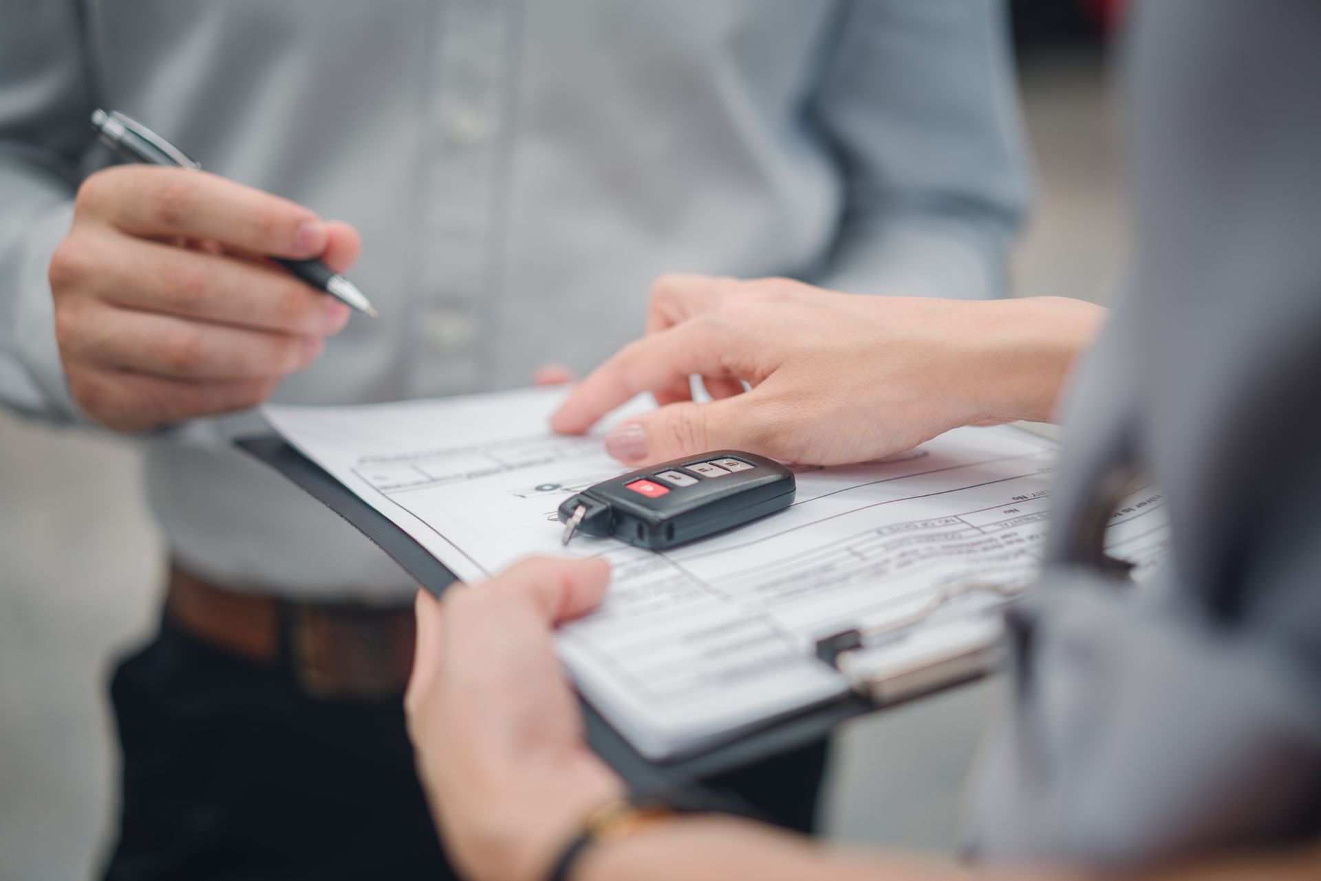 Hands reviewing a contract with a calculator on a clipboard in an office setting
