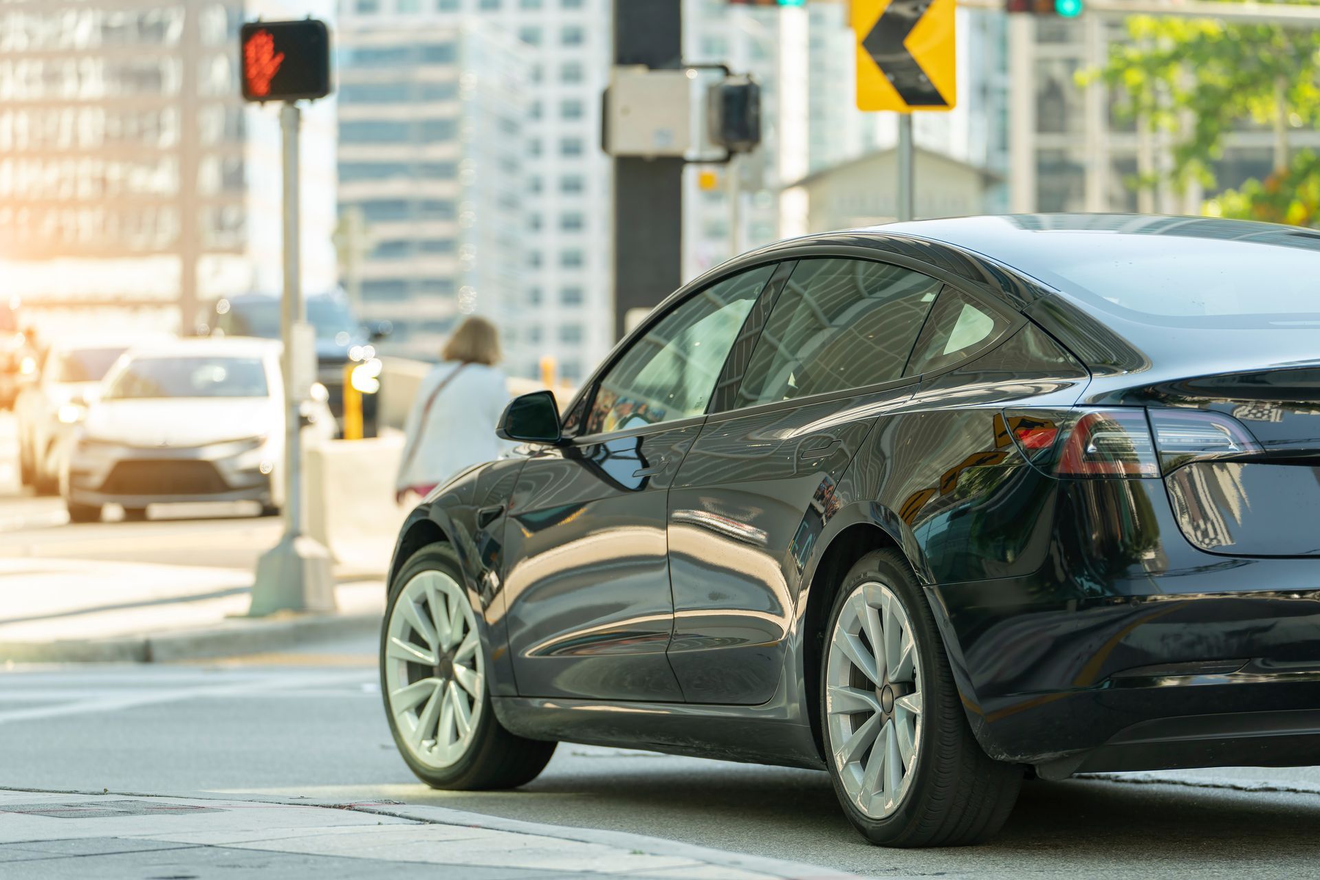 Black sedan at a city intersection, turning near a crosswalk and traffic light. Black sedan at a city intersection, turning near a crosswalk and traffic light.