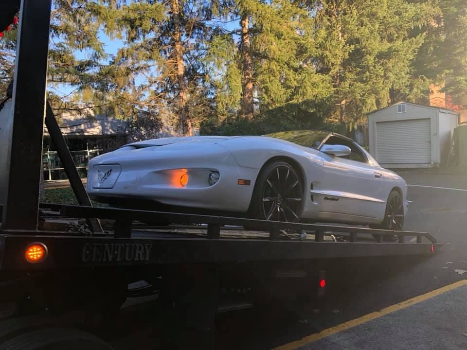 A white sports car is being towed by a tow truck.