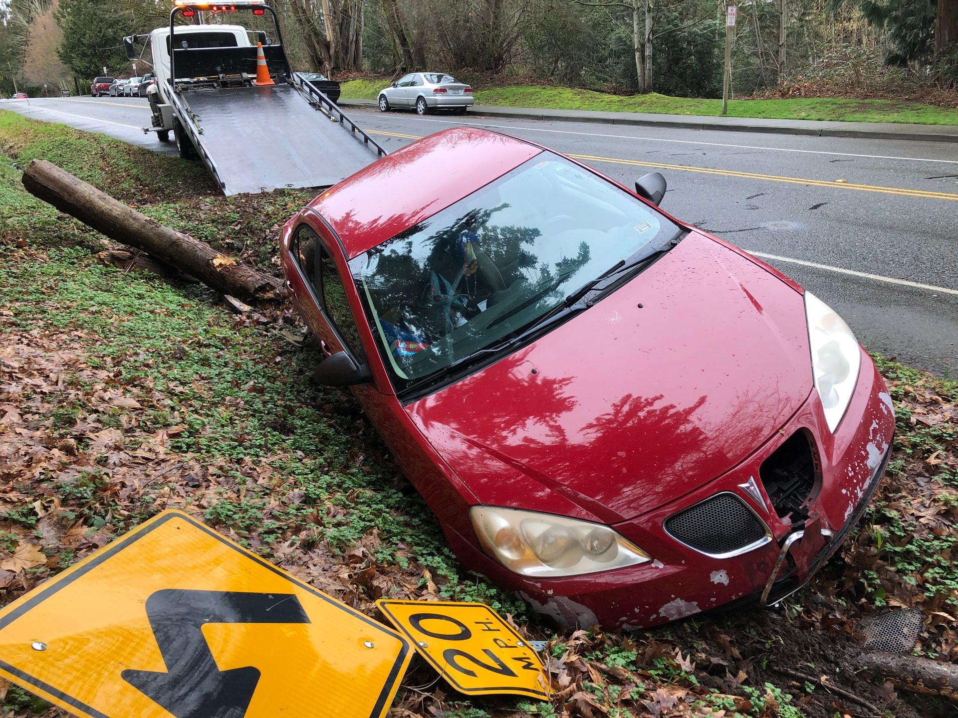 A red car is laying on the side of the road next to a sign that says 20