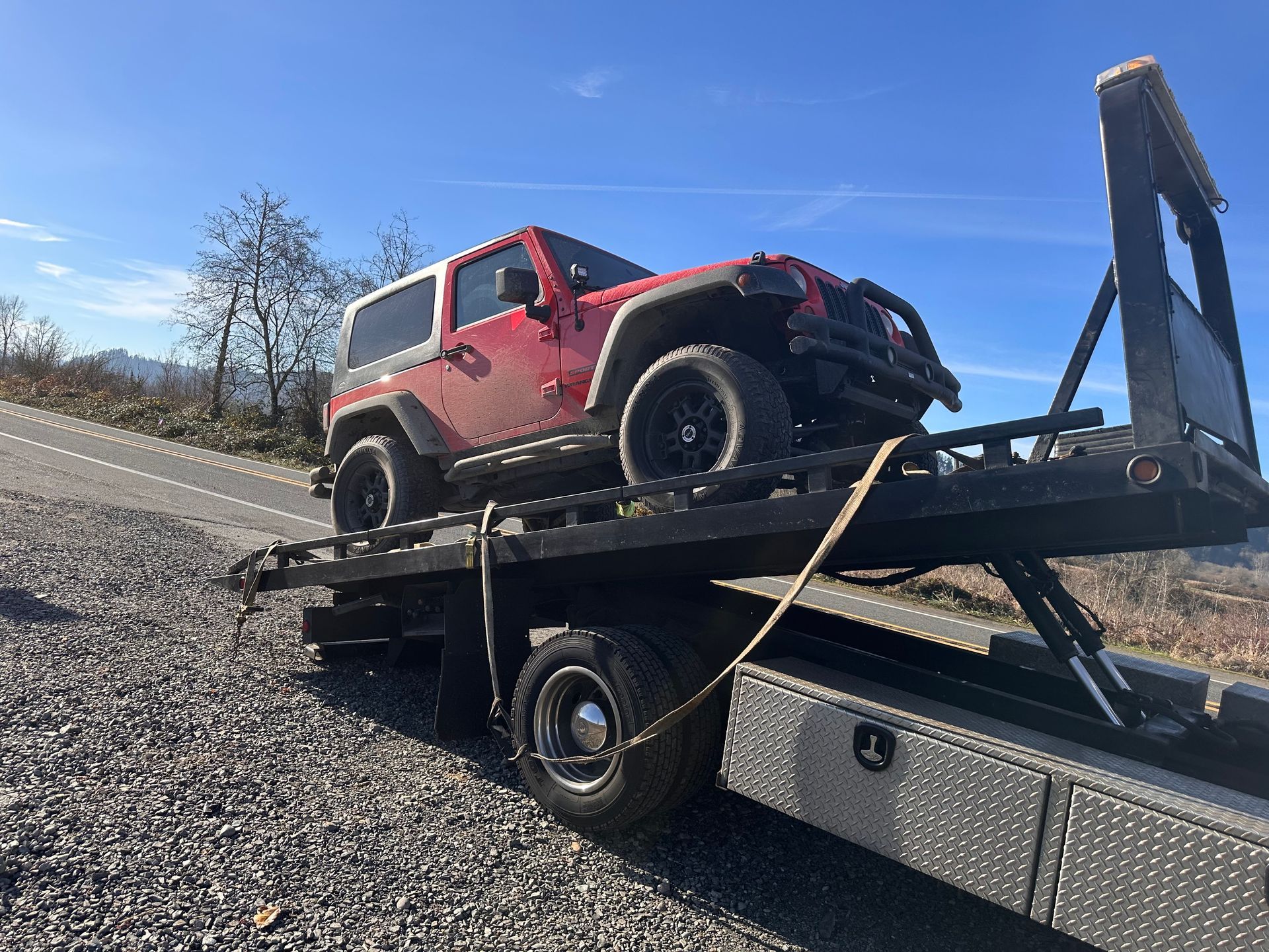 A red jeep is sitting on top of a tow truck.