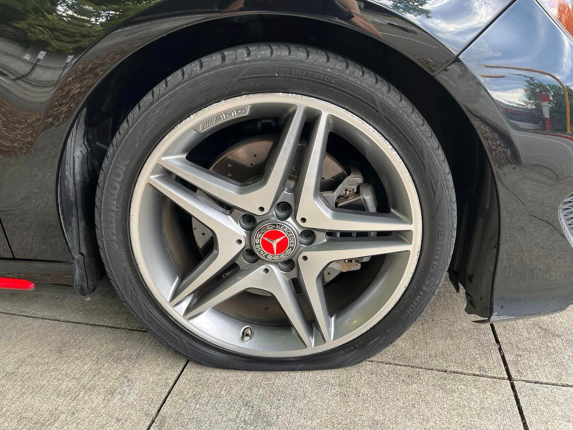 A black car with a flat tire on the side of it.