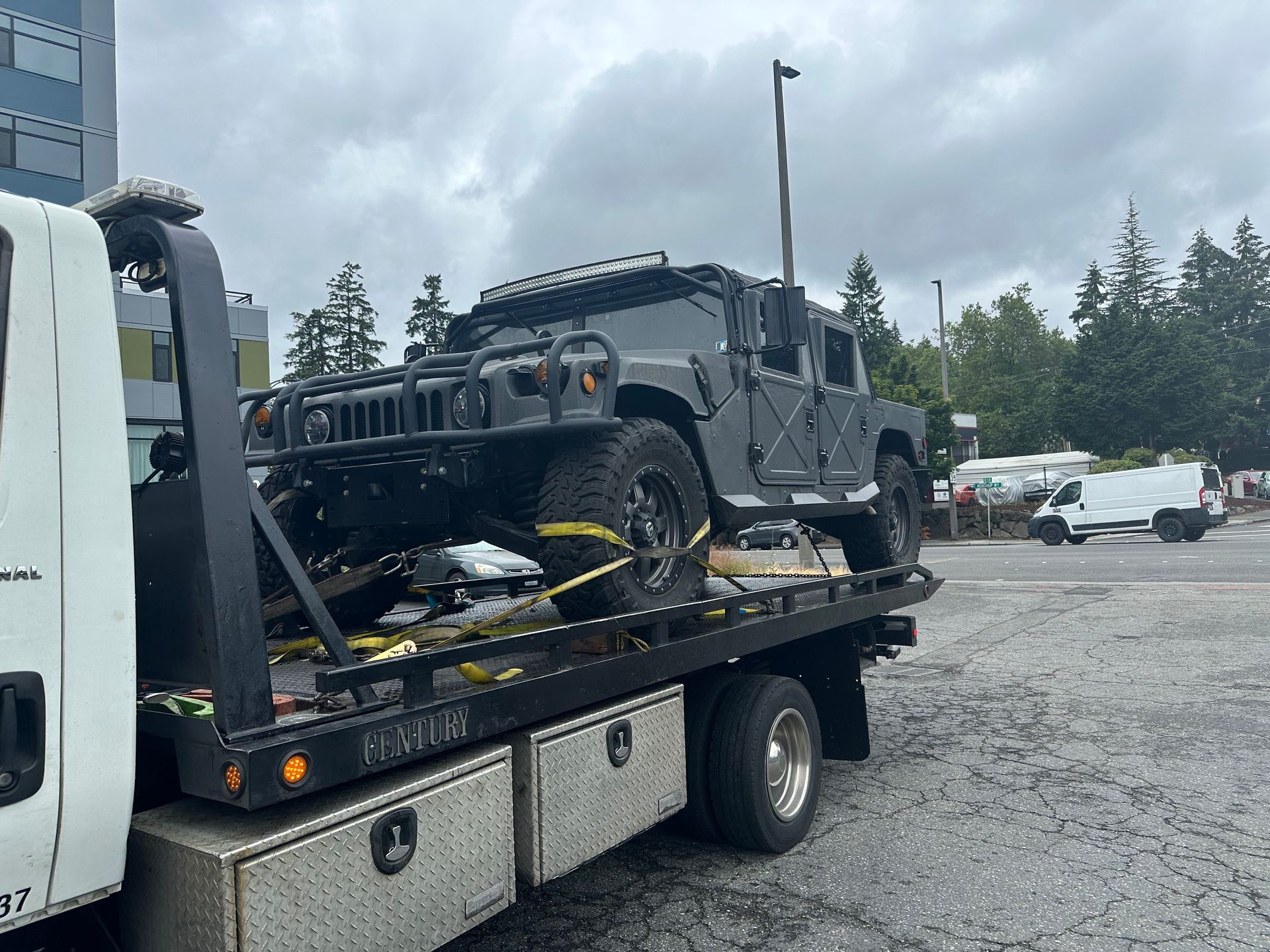 A hummer is being towed by a tow truck.
