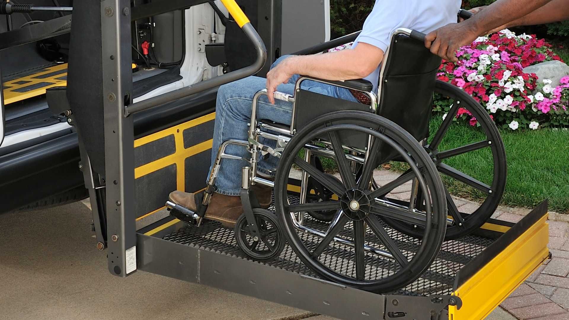 A man in a wheelchair is being lifted into a vehicle on a wheelchair lift