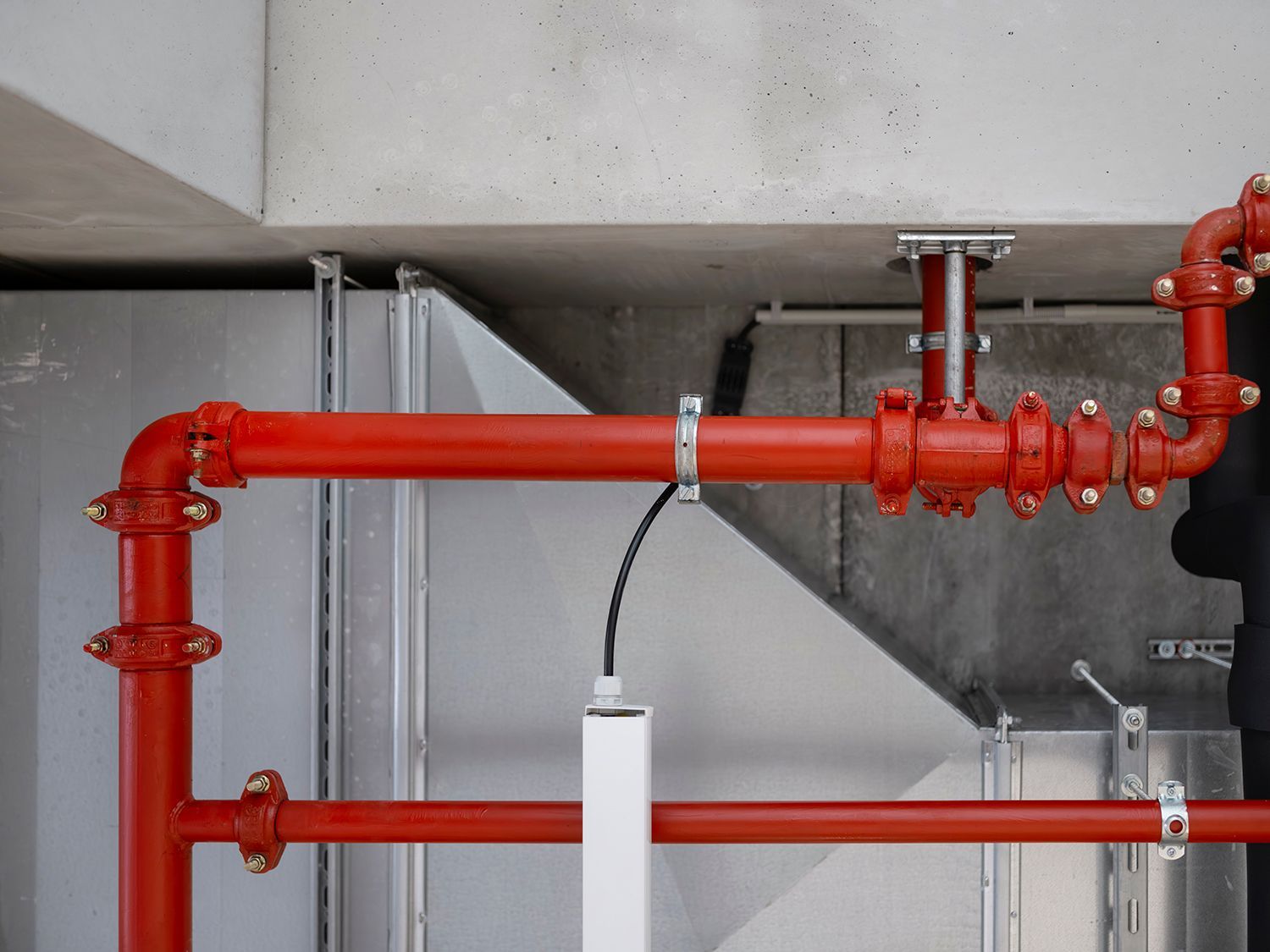Red fire sprinkler pipes mounted under a concrete ceiling in an industrial space Red fire sprinkler pipes mounted under a concrete ceiling in an industrial space