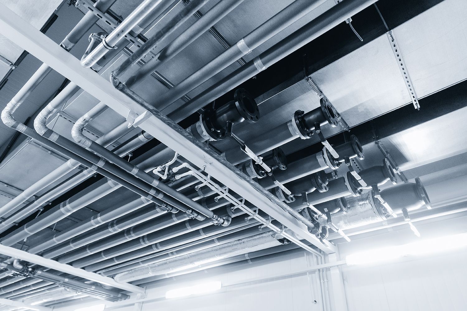 Ceiling view of metal pipes and ducts in an industrial utility room Ceiling view of metal pipes and ducts in an industrial utility room