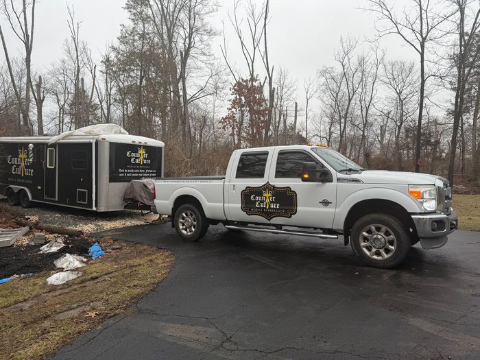 A white Ford pickup truck towing a black trailer with