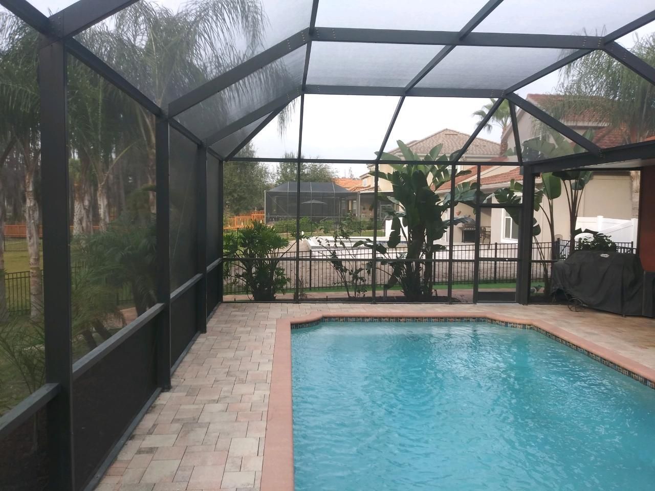 A Screened in Swimming Pool With a House in the Background - Spring Hill, FL - The Screen King of Tampa, Inc