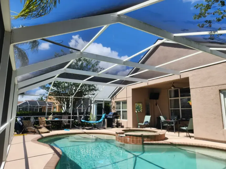 Backyard patio with screened enclosure, outdoor chairs, umbrella, and trees beyond the fence