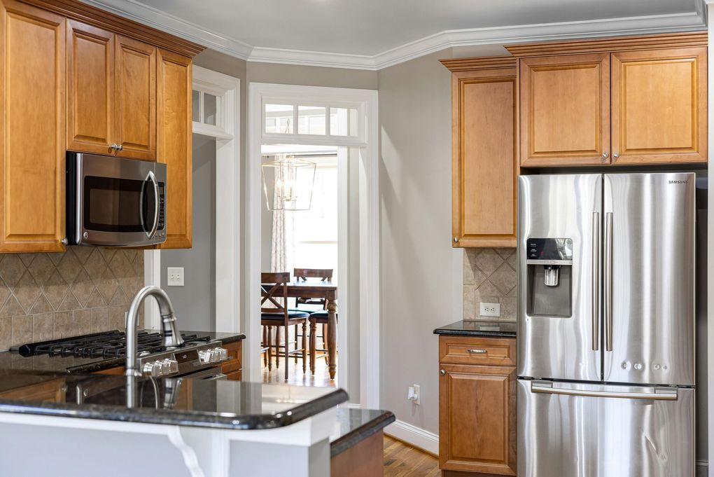 Kitchen with wooden cabinets, stainless steel appliances, and a view into a dining room.